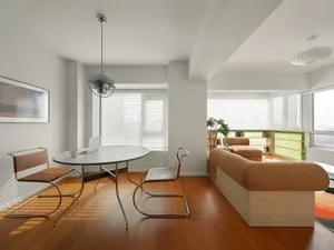 A modern minimalist living room featuring a wooden floor, beige couch, and minimalist furniture.