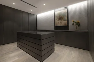 A modern office reception desk with dark wood finish and a vase of flowers on the counter.