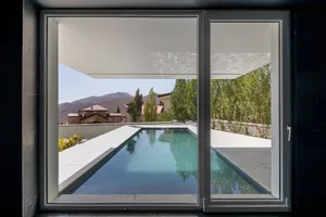 A modern poolside view featuring concrete and glass elements.