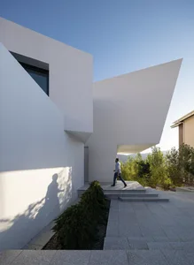A modern residential exterior with a curved concrete wall and large window