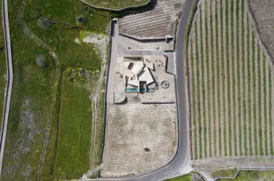 Aerial view of a modern residential house with a concrete foundation and surrounding greenery.