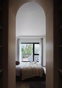 View of a minimalist bedroom with wooden furniture and fabrics.