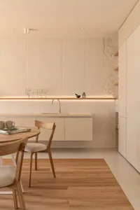 Modern minimalist kitchen featuring concrete walls, stone countertops, and wooden flooring.
