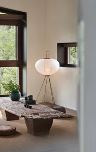A minimalist living room featuring a wooden table, lamp, and green plant.