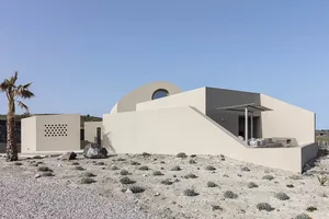 A minimalist residential exterior featuring sandstone, glass, and concrete materials.