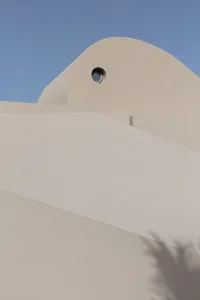 Minimalist building with curved concrete roof and round window.