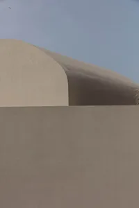 A minimalist sand hill with smooth, curved surfaces under a clear blue sky.