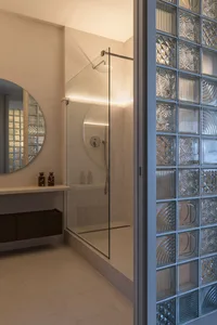 A modern bathroom with glass brick paneling and a walk-in shower.