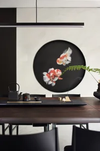 Modern dining room with minimalist black and wood furniture, a large circular art piece depicting fish, and an incense stick 