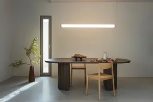 A modern dining room featuring a wooden table with a minimalist design, accompanied by chairs and a plant in a vase, with a l