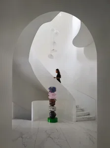 Modern interior design featuring a glass staircase with colorful sculptures and an abstract art installation