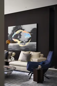 A modern living room with a blend of materials, featuring a sofa, a blue armchair, a coffee table, and a large abstract paint