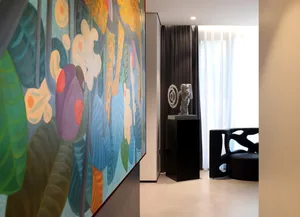 A modern living room featuring a large, colorful artwork on the wall, a sculptural astronaut figure, and a contemporary black