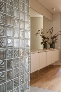 Modern living room featuring a glass block wall with a wooden floor and white cabinets.