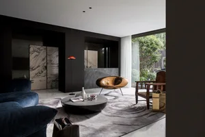 Modern living room featuring a sleek, curved wooden armchair, a round coffee table, and a dark, textured sofa, with large win