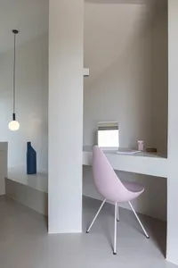 Modern minimalist home office with concrete desk, metal chair, and floating shelves.