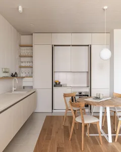 A modern minimalist kitchen with light wooden furniture and clean, sleek appliances.