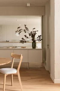 Modern minimalist kitchen interior with wood accents and a vase of dried branches.