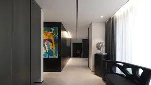 A minimalist living room featuring metal and glass furniture with wooden accents and a vibrant abstract painting.