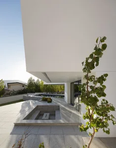 Modern residential outdoor space featuring a pool with concrete deck, glass railings, and steel elements.