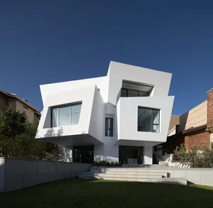 A minimalist, modern residential building featuring white concrete and glass exteriors.