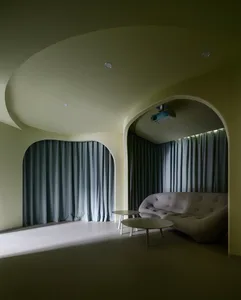 A minimalist interior design featuring curved spaces, curtains, and a couch with a relaxed seating arrangement.