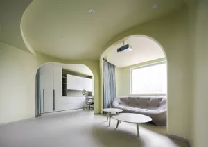 Modern, minimalist living room with white furniture, grey sofa, and white coffee tables.