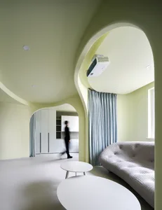 A modern white living room with a curved arch ceiling, a gray sofa, and white tables.