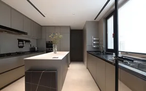 Modern minimalist kitchen with white countertops, concrete flooring, and glass window.