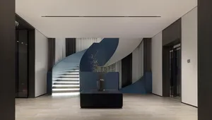 A modern lounge area featuring a metallic staircase and minimalist decor.