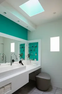 A modern minimalist bathroom with a concrete sink, mirror, and shelving unit.