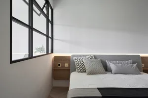 Modern minimalist bedroom featuring a white and grey textile bedspread, a grey upholstered headboard, and wooden accents.
