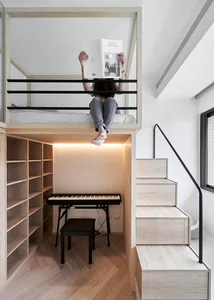 A modern living space featuring a floating bed with an integrated desk, stairs, and a piano.