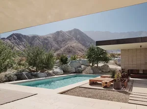 A modern minimalist exterior with a concrete pool and surrounding natural landscape.