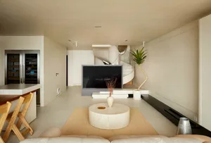 Minimalist living room with concrete floor, wooden furniture, and glass walls.