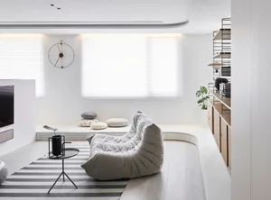 Modern minimalist living room with wood flooring, a grey tufted sofa, and a striped rug.