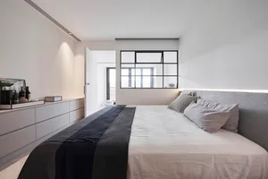 現代簡約臥室搭配白色家具與黑色點綴，設有大型床鋪及灰色絨布床頭板