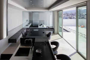 Minimalist kitchen featuring black glass countertop and metal fixtures