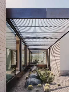 Modern desert garden featuring concrete, glass, rocks, and cactus plants.