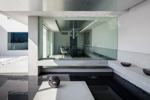 Modern minimalist interior space featuring glass walls and a concrete floor.