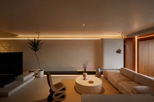 Modern living room with neutral colors, featuring a sofa, coffee table, and potted plant.