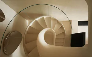 A minimalist staircase with a glass railing and concrete steps.