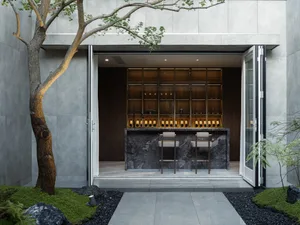 Modern minimalist bar counter with marble countertop and concrete walls and floors, featuring wood accents and a sleek design
