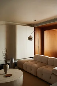 Modern living room with neutral-toned furniture, circular coffee table, and floor lamp.