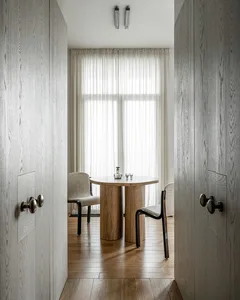Modern dining room with wooden table and chairs, minimalist design, and large window for natural light.