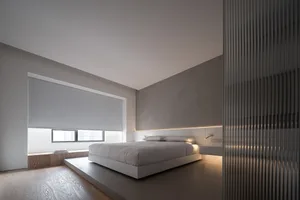 A minimalist bedroom featuring a concrete bed platform with built-in lighting.