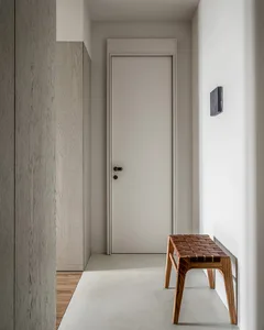 A modern entryway featuring a wooden furniture piece and a closed door.