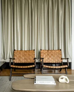 Modern interior design featuring wooden floor and beige curtains with two woven leather chairs