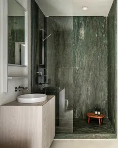 A modern bathroom featuring green marble walls and a minimalist wooden vanity sink.