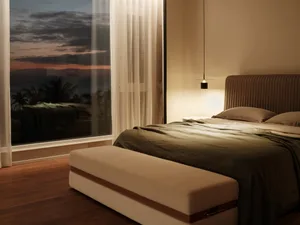 A modern bedroom featuring a brown upholstered bed with a fabric headboard, illuminated by a hanging pendant light, and a lar